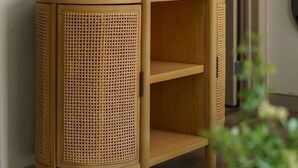 Un mueble de esquina con panel frontal tejido, un pequeño estante y un marco de foto en la parte superior.