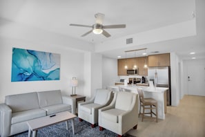 A modern living room with a sofa, armchairs, a coffee table, and a painting on the wall.
