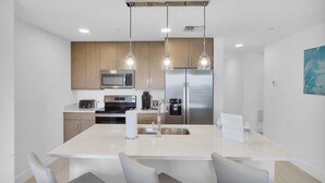A modern kitchen with a central island, stainless steel appliances, and pendant lighting.