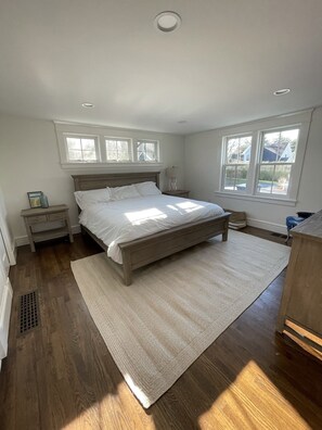 Ein Schlafzimmer mit einem großen Bett, zwei Nachttischen, einem Schranken und einem Fenster sowie einer Heizung.