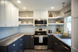 A modern kitchen with dark cabinets, a stainless steel oven, a microwave, and a sink.