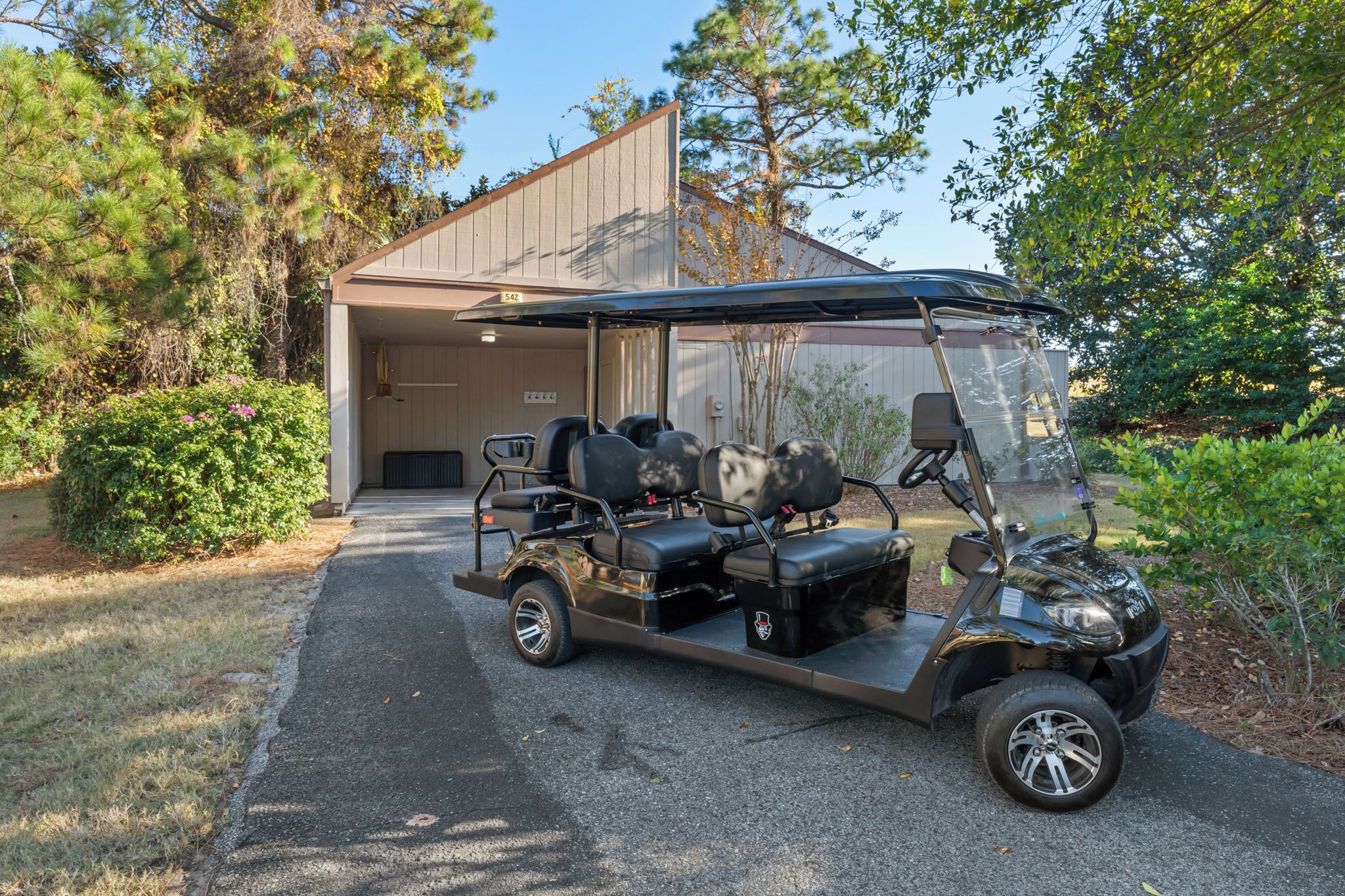Une voiturette de golf est garée devant un bâtiment dont la porte de garage est visible.