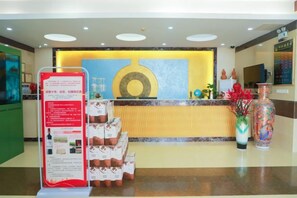 A hotel reception area with a counter, informational posters, and a decorative vase. - Renrenshun Hotel (Haifeng)
