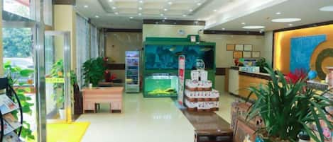 A hotel lobby with a reception desk, seating area, and a large potted plant.
