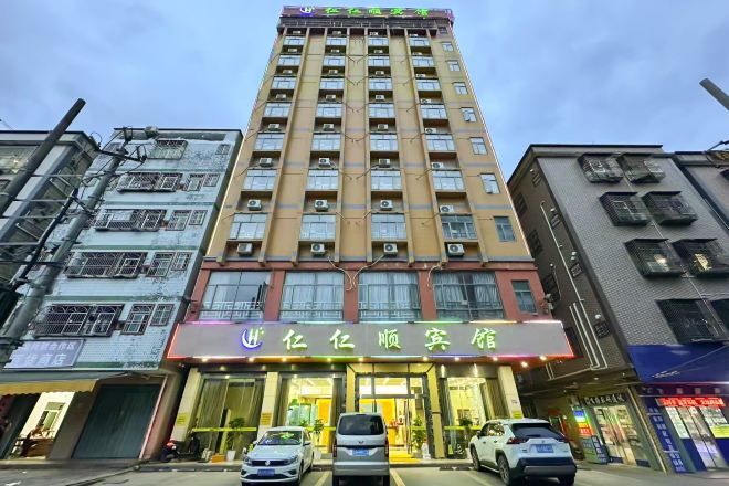 Un hotel de varios pisos con una entrada destacada, unidades de aire acondicionado y una tienda con señalización visible.
