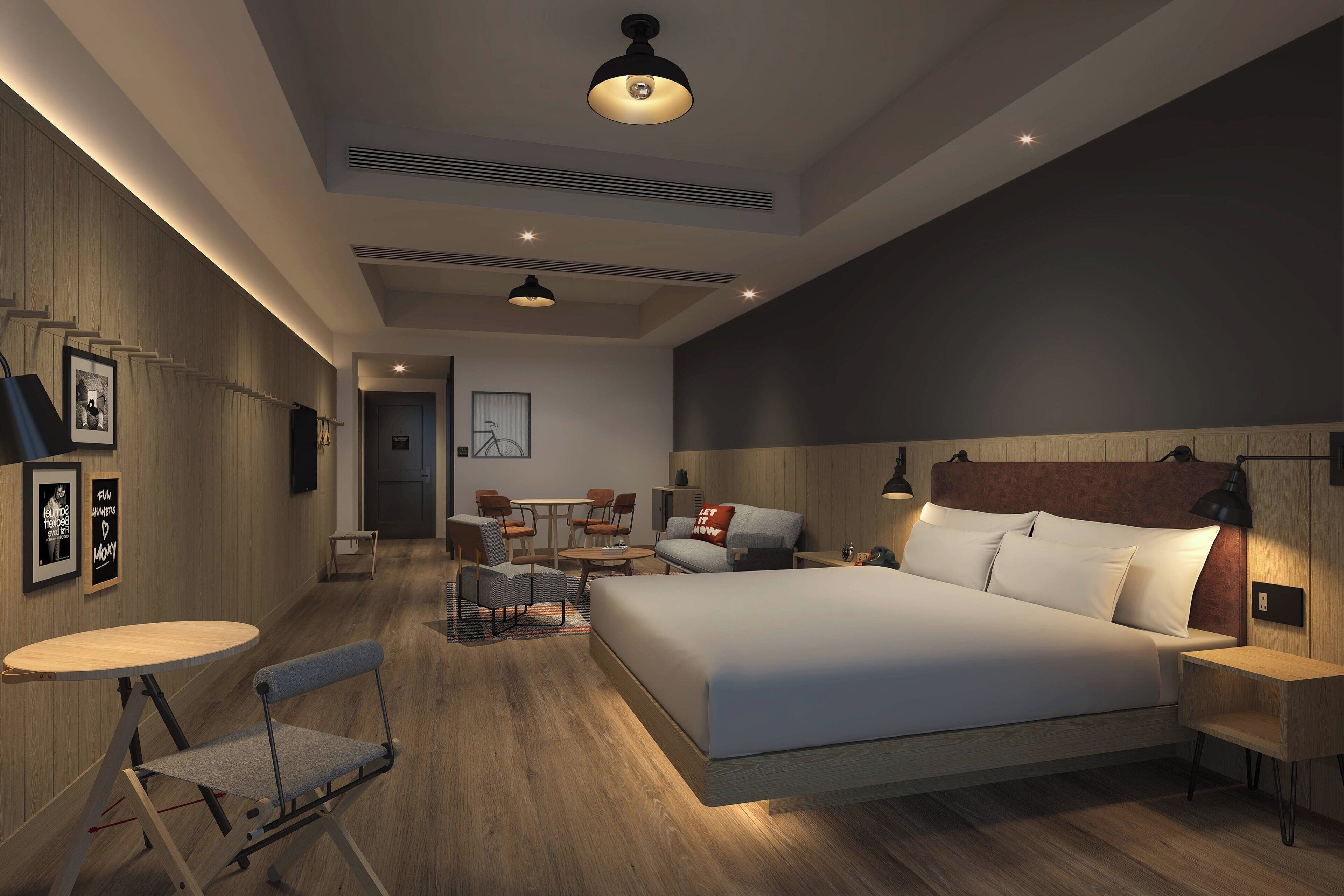 Ein modernes Hotelzimmer mit einem großen Bett, einer Sitzecke mit Tisch und Stühlen sowie einem kleinen Schreibtisch.
