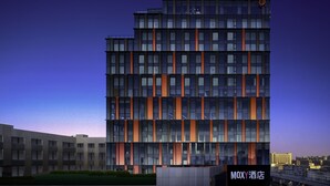 A modern hotel building with multiple floors, large windows, and a sign reading "MOXY  酒店" at the bottom. - Moxy Nanjing Jiangning (Nanjing)