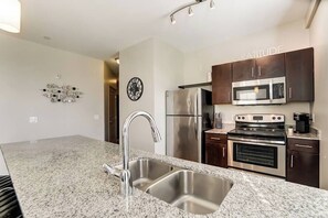 Una cocina moderna con encimeras de granito, electrodomésticos de acero inoxidable y armarios de madera oscura.