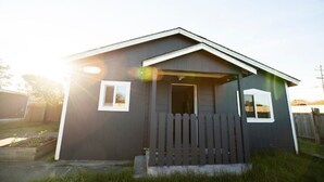 Una casa pequeña de color oscuro con un porche y una valla de piquetes.