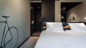 A modern hotel room with a large bed, a bicycle art installation on the wall, and a shower area. - Hotel Valkenburg by Mercure (Valkenburg aan de Geul)