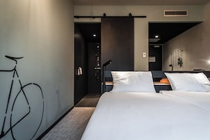 Een moderne hotelkamer met een groot bed, een fietskunstinstallatie aan de muur en een douchegedeelte.