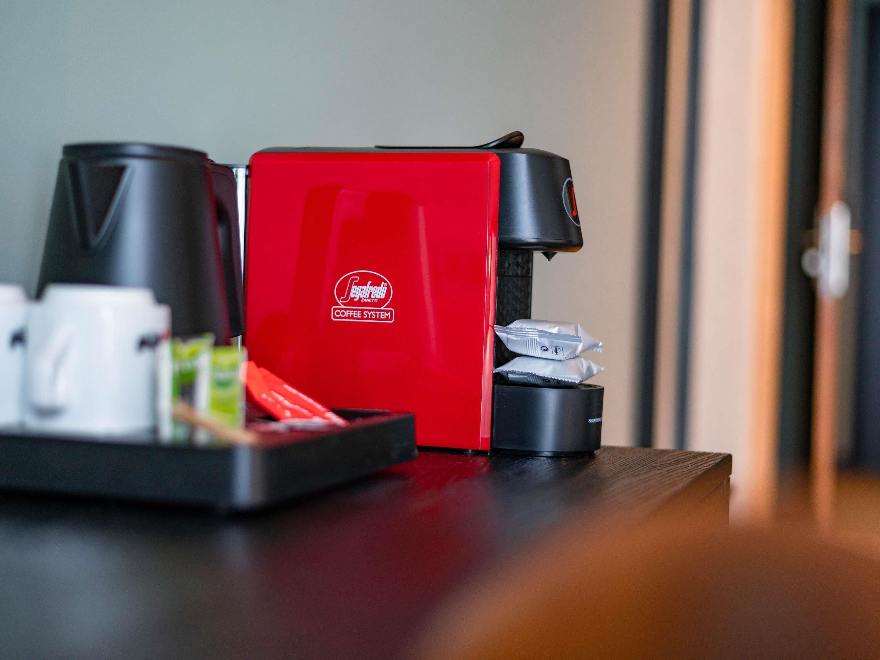 Una cafetera roja con un portacapsulas sobre una mesa.