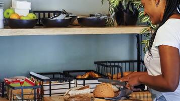 Una cocina con tabla de cortar, pan y una persona cortando pan.