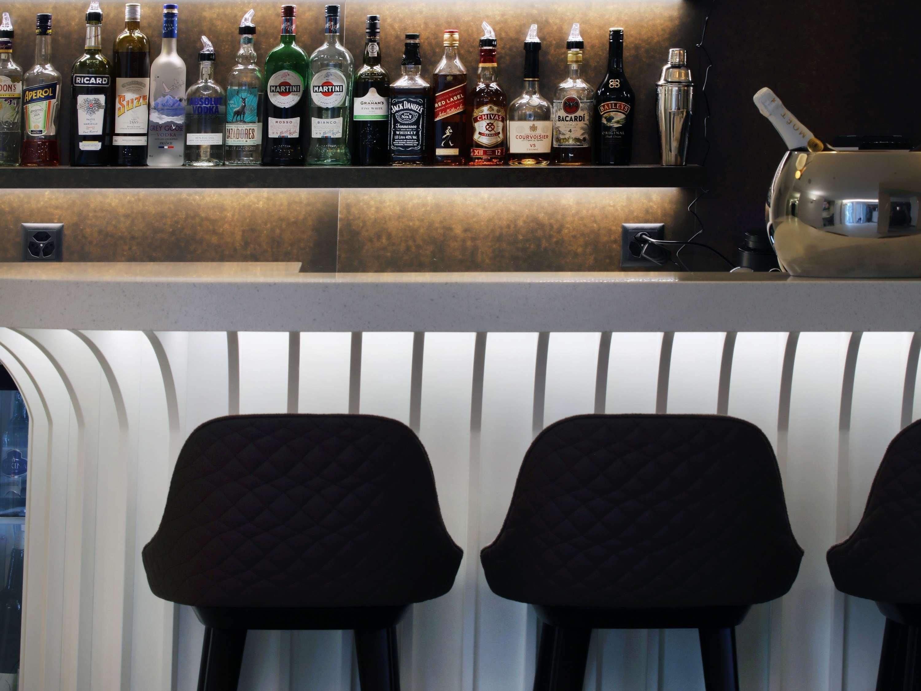 A bar area with various liquor bottles and two upholstered bar stools.