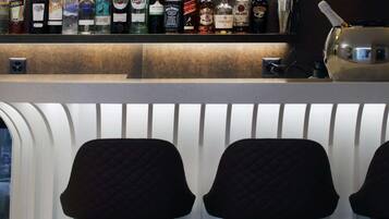 A bar area with various liquor bottles and two upholstered bar stools.