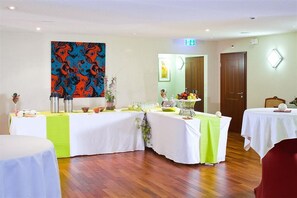 A conference room with tables set for a meeting, a large abstract painting on the wall, and a door with a light above it. - Mercure Fribourg Centre Remparts (Fribourg)