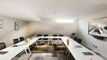 A conference room with a long table, chairs, a projector screen, and a large window.
