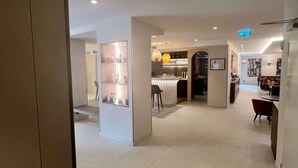 A hotel lobby with a reception desk, a seating area with chairs, and a bar. - Mercure Fribourg Centre Remparts (Fribourg)
