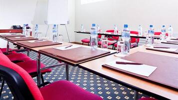 Un salón de conferencias con mesas, sillas, botellas de agua y una pizarra.