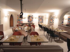 A restaurant with multiple dining tables, chairs, and a bar area. - Mercure Fribourg Centre Remparts (Fribourg)
