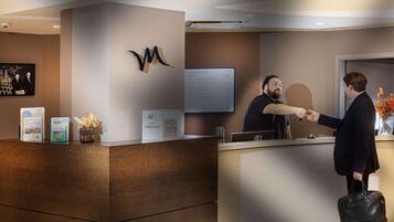 A reception desk with a modern design, a mounted logo, a digital screen displaying rates, and a key box.