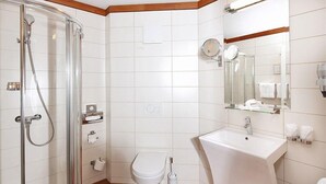 Un baño moderno con cabina de ducha de vidrio, inodoro blanco, lavamanos y espejo sobre él.