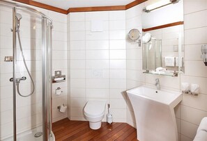Ein modernes Badezimmer mit Duschkabine aus Glas, Toilette in Weiß, Waschbecken und einem Spiegel darüber.