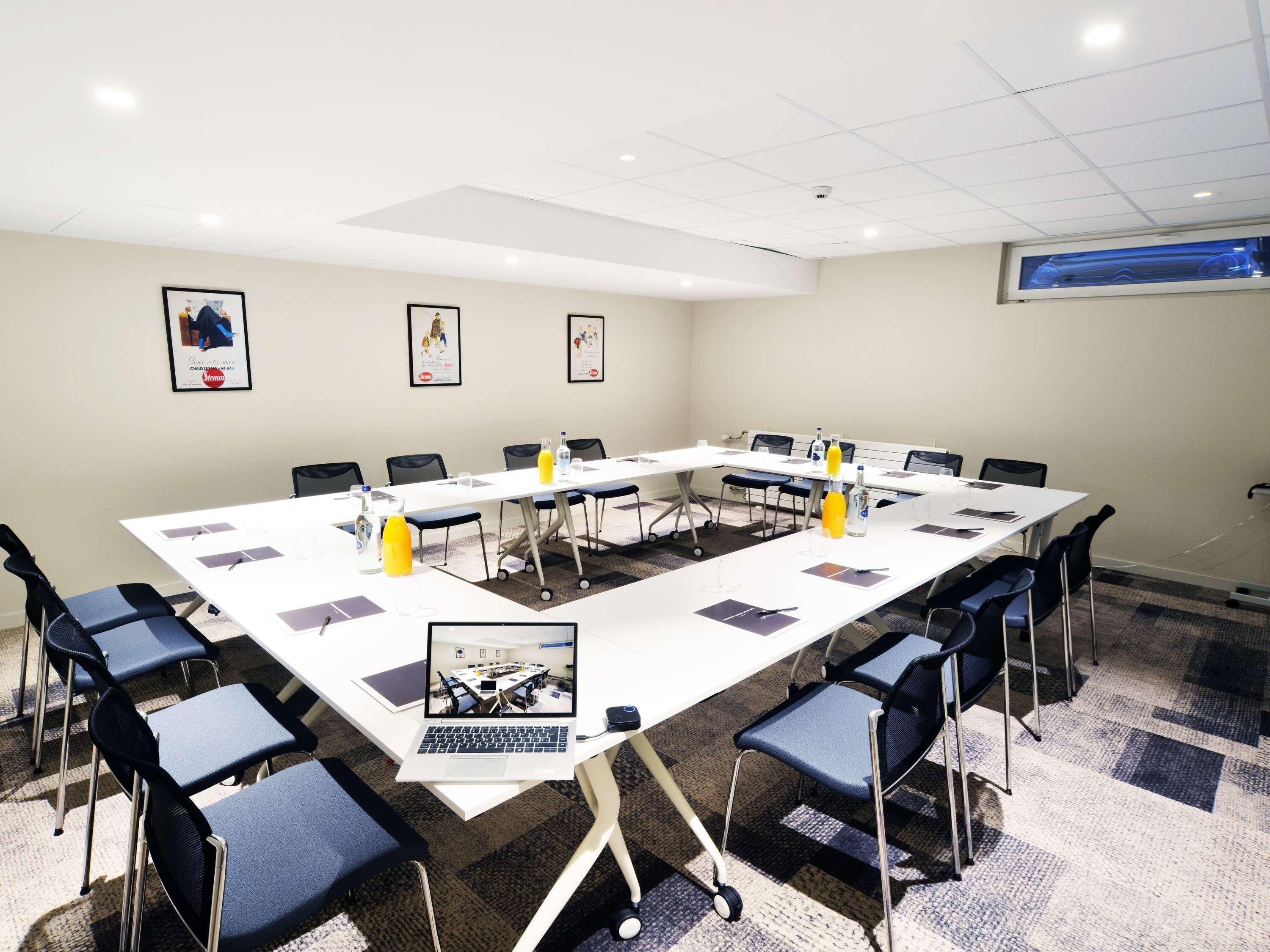 A conference room with a long table, chairs, laptops, and water bottles.