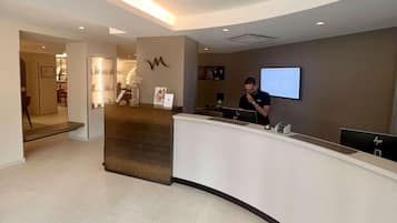 A reception desk with a computer, a framed picture, and a wall-mounted screen.