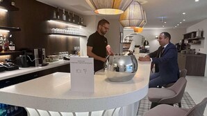 A modern bar area with a bar counter, a unique metallic bowl centerpiece, and seating for guests. - Mercure Fribourg Centre Remparts (Fribourg)