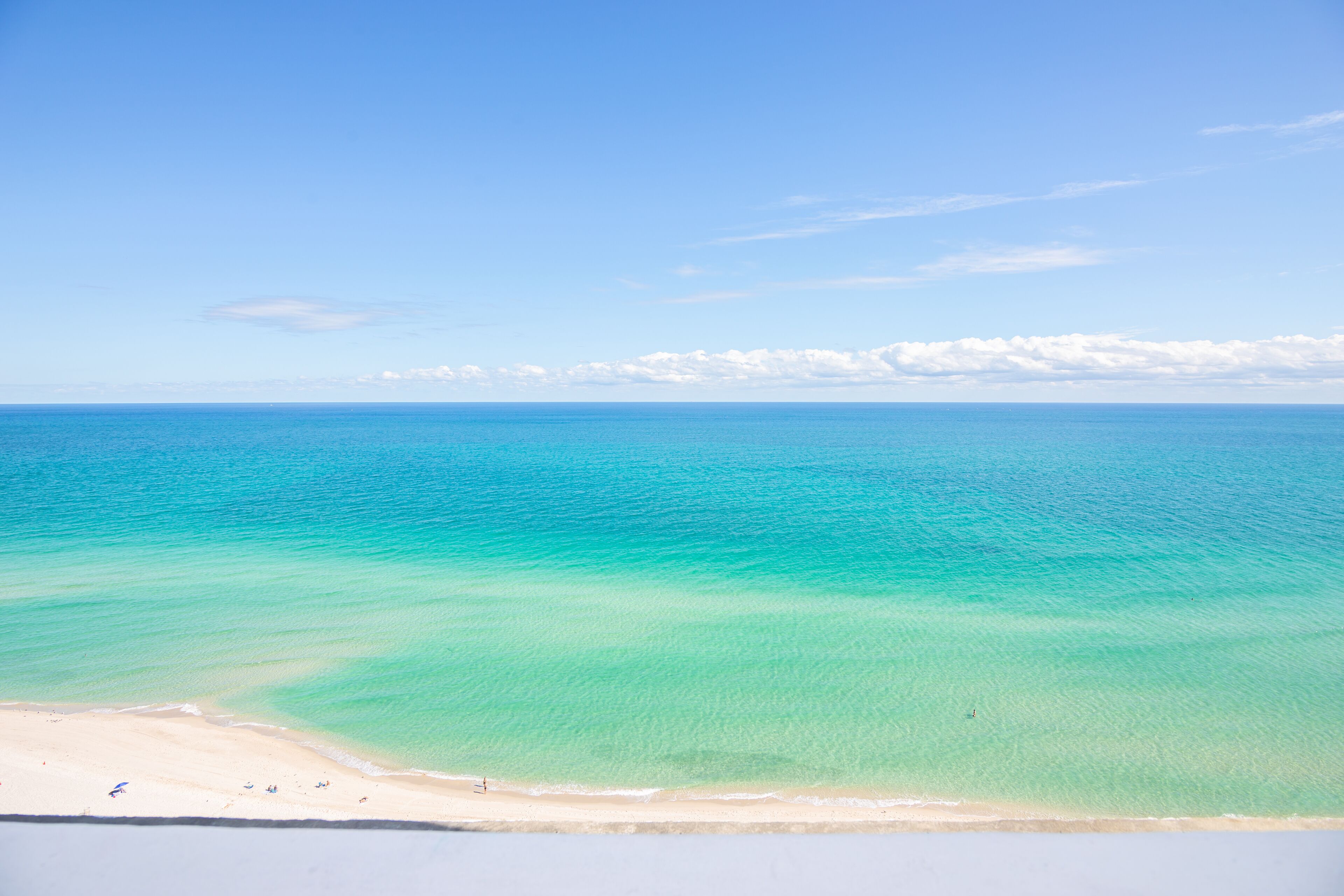 A beach with clear turquoise water and a sandy shore.