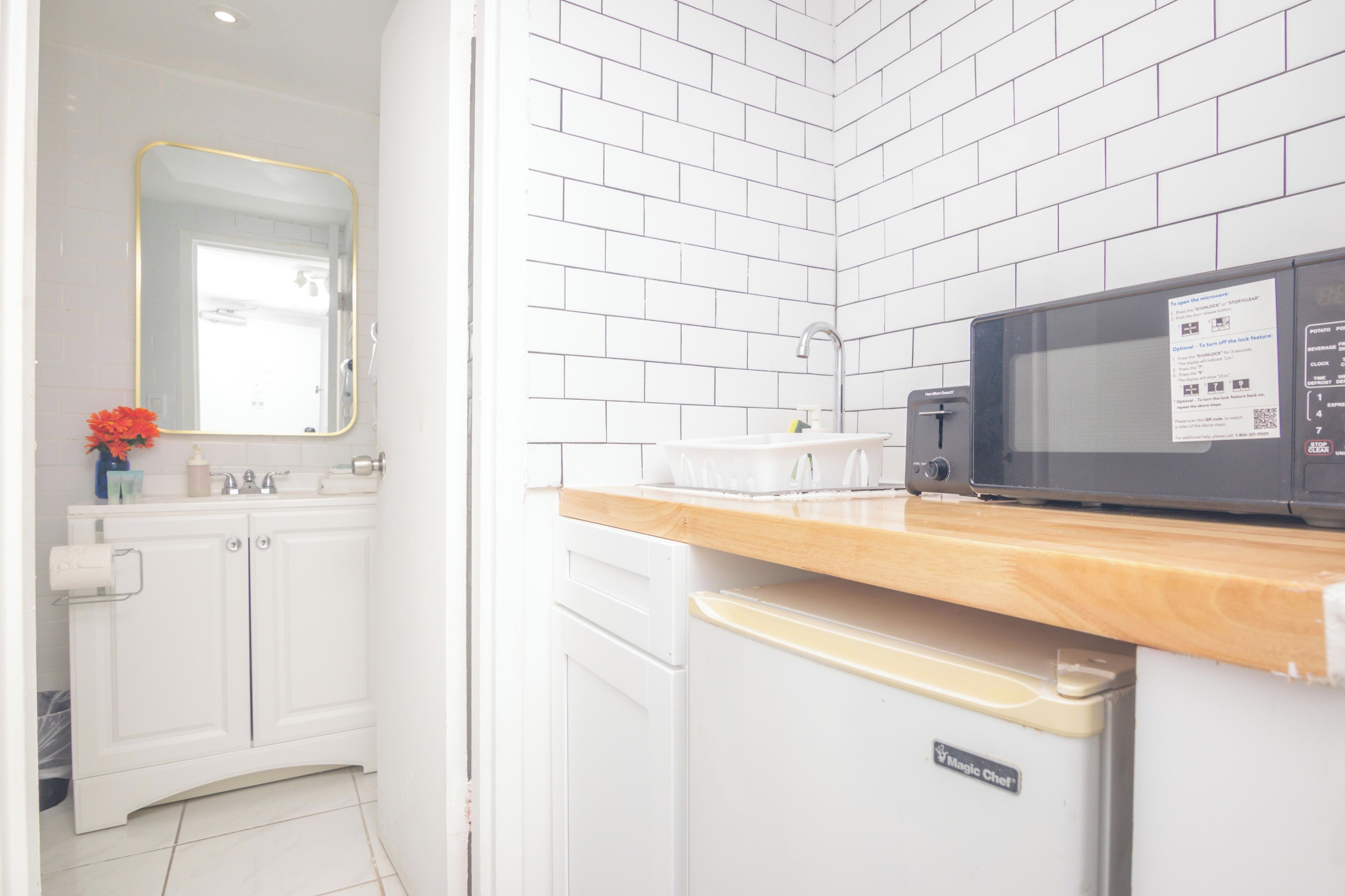 Una cocina moderna con armarios blancos, encimera de madera, microondas y lavavajillas.