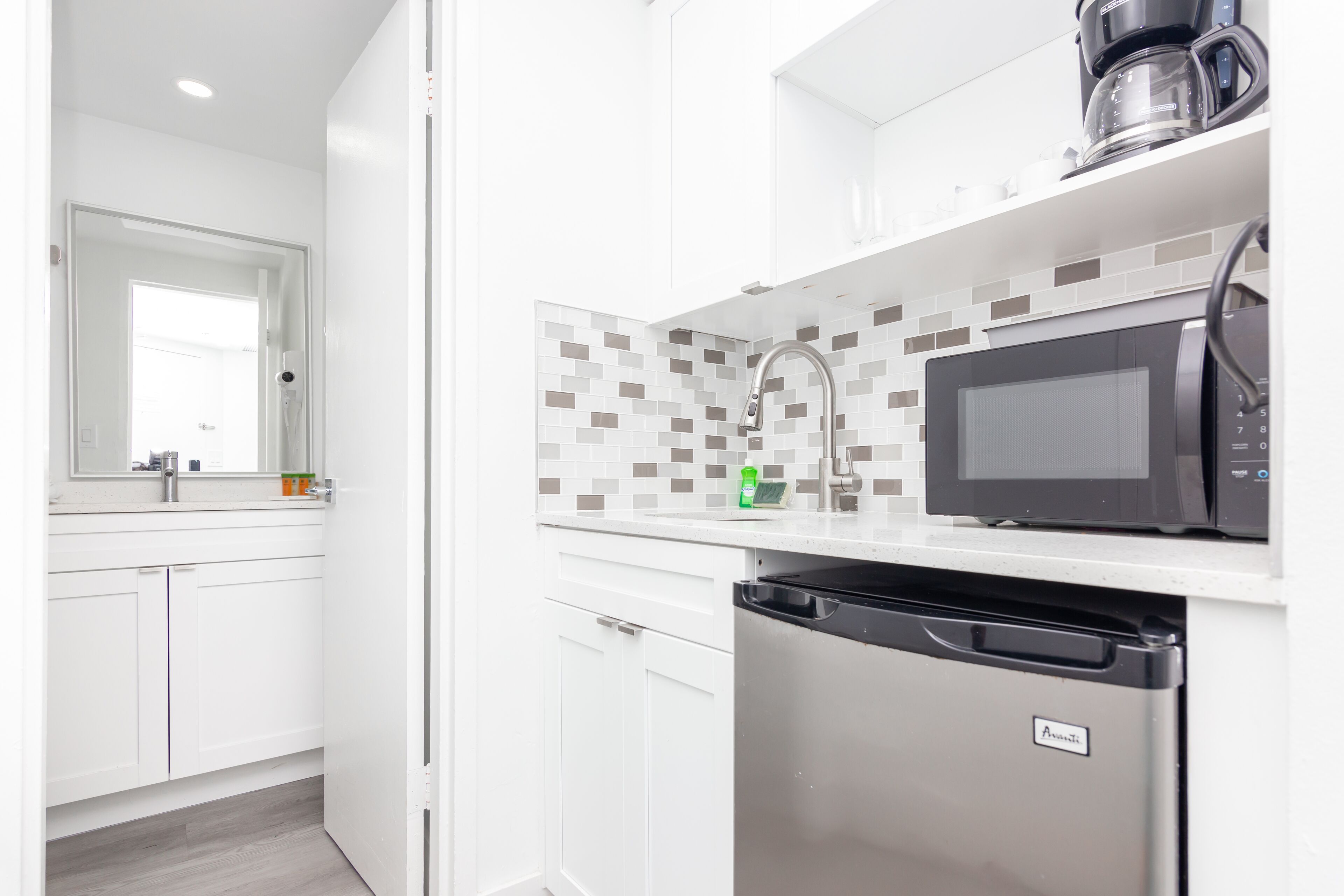 A modern kitchen with white cabinets, a black microwave, and a dishwasher.