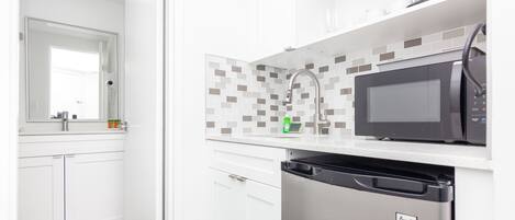 A modern kitchen with white cabinets, a black microwave, and a dishwasher.