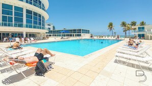Un espace piscine avec des chaises longues et un bâtiment doté de grandes fenêtres.
