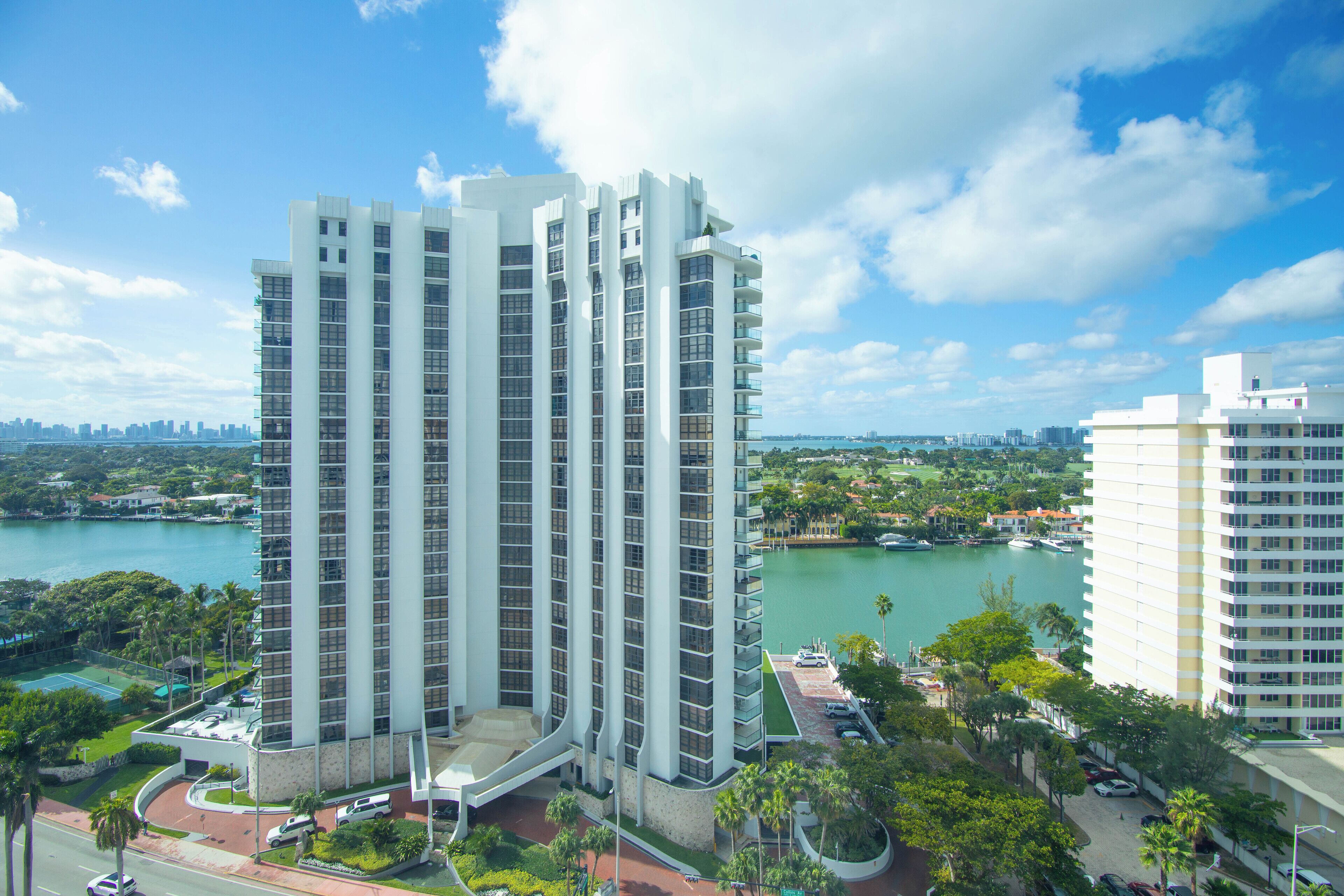 Un hôtel de grande hauteur, avec de nombreux étages, offrant une vue sur le front de mer et entouré d’un parc.