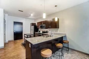 Una cocina moderna con una isla central, taburetes de bar y armarios de madera.