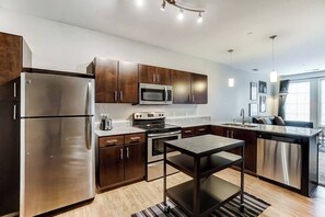 A modern kitchen with stainless steel appliances, dark wood cabinets, and a central island.
