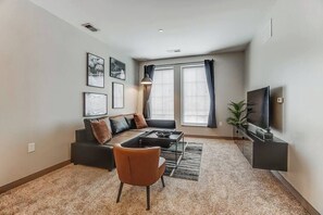 A modern living room with a sofa, armchair, coffee table, and TV.