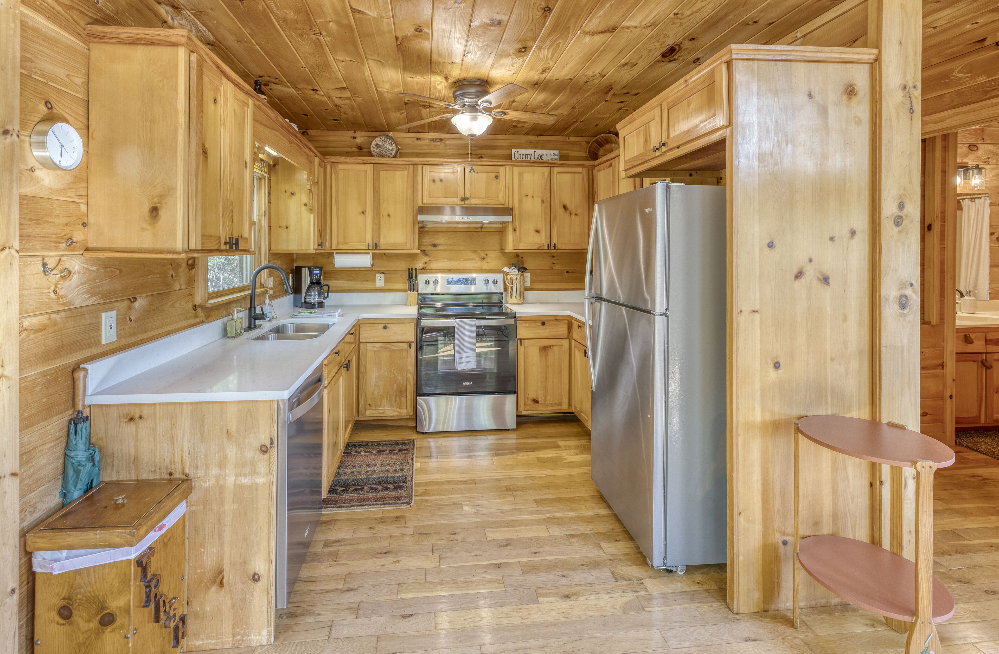 A wooden cabin-style kitchen with a central island, stainless steel appliances, and a ceiling fan.