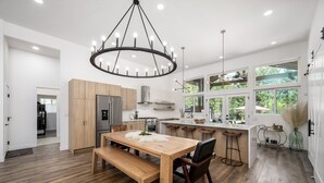 Eine moderne Küche mit Holztisch, integrierten Geräten und großen Fenstern.
