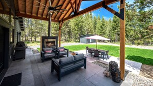 Eine Terrasse im Freien mit eingebautem Kamin, Sitzbereich und Deckenventilator.
