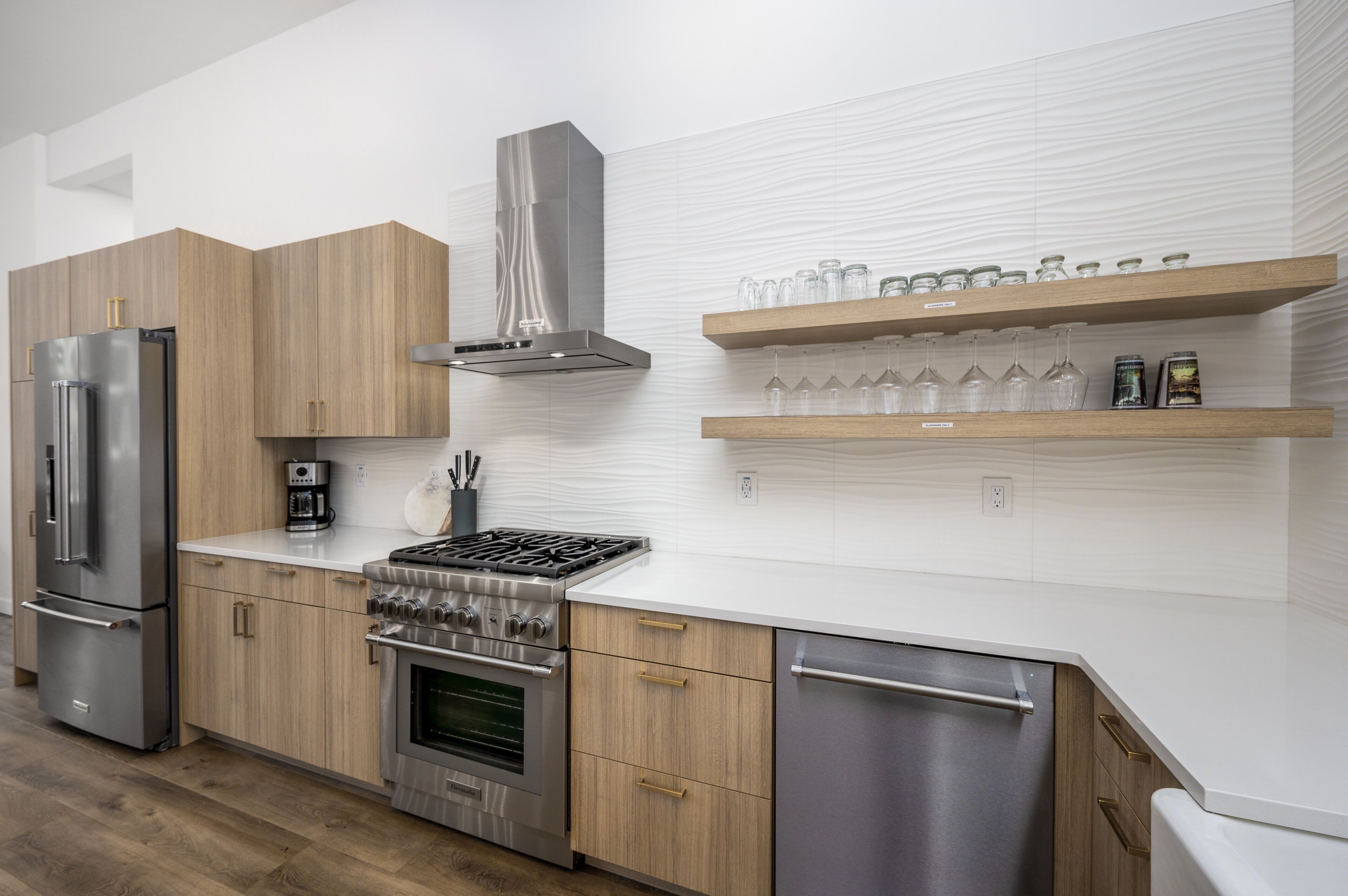 Une cuisine moderne dotée d’appareils électroménagers en acier inoxydable, de meubles en bois et d’un dosseret de carrelage blanc.