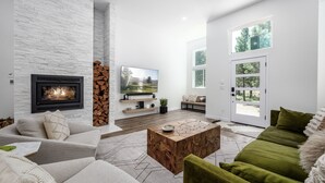 Ein modernes Wohnzimmer mit Kamin, Flachbildfernseher und großem Fenster.