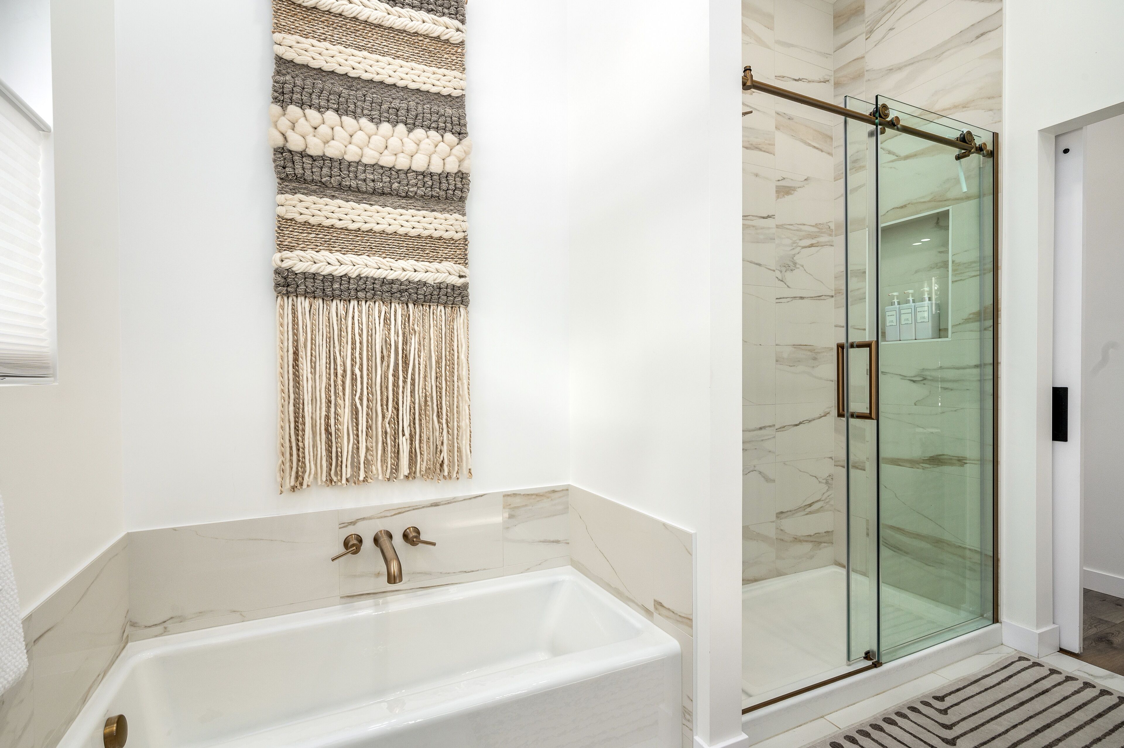 Une salle de bain moderne avec une baignoire sur pieds, une douche à parois de verre et une décoration murale en macramé.