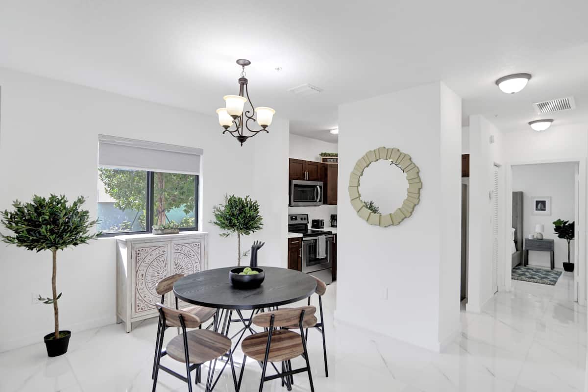A modern kitchen with dark cabinets, a central island, and a hanging light fixture.