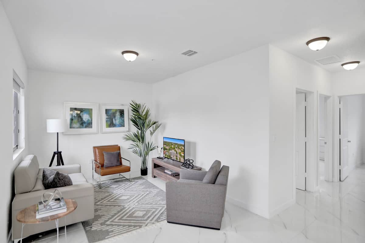 A modern living room with a sofa, armchair, coffee table, and a TV on a stand.
