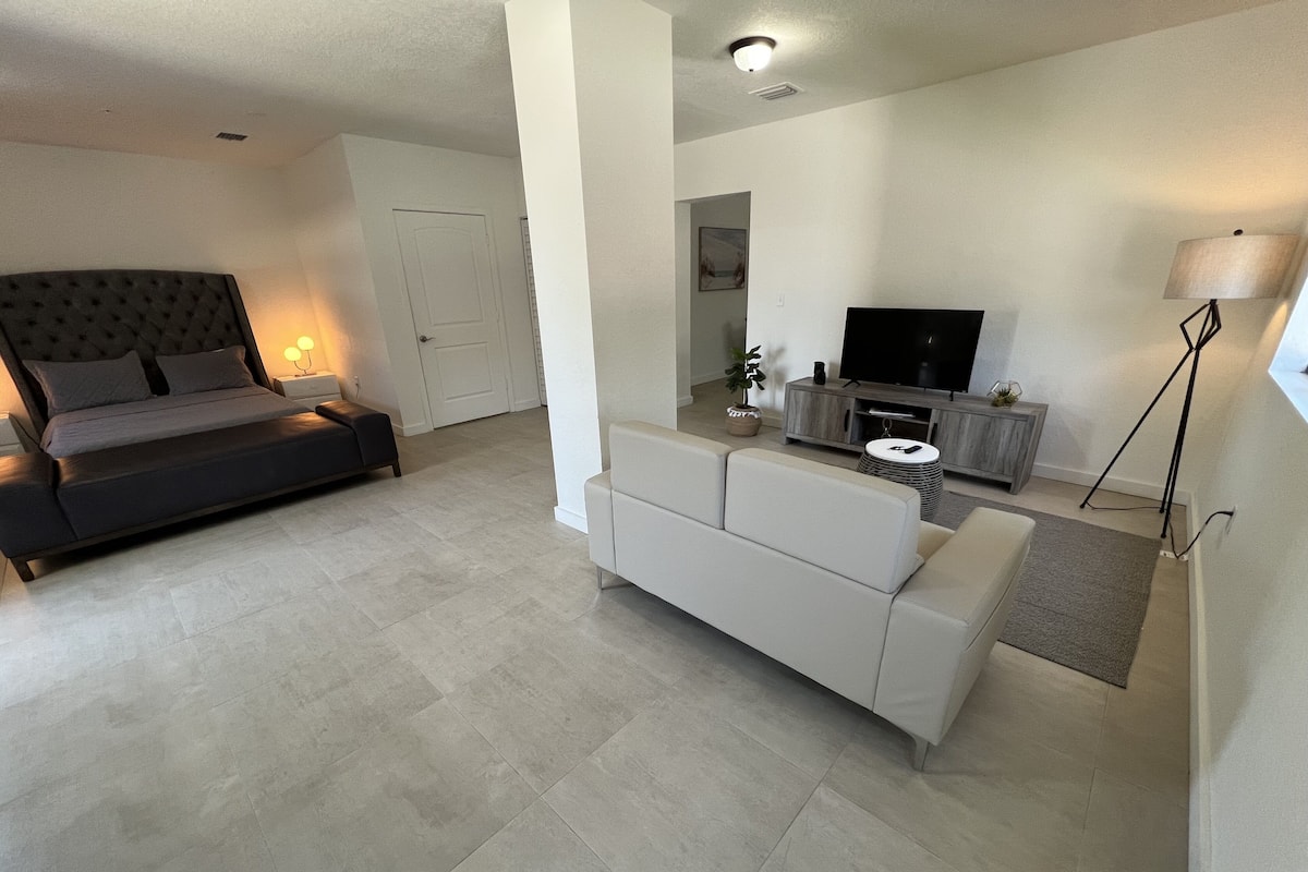 A modern living room with a sofa, a TV, and a lamp.