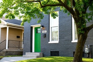 A two-story building with a green door and a mailbox marked '930'.