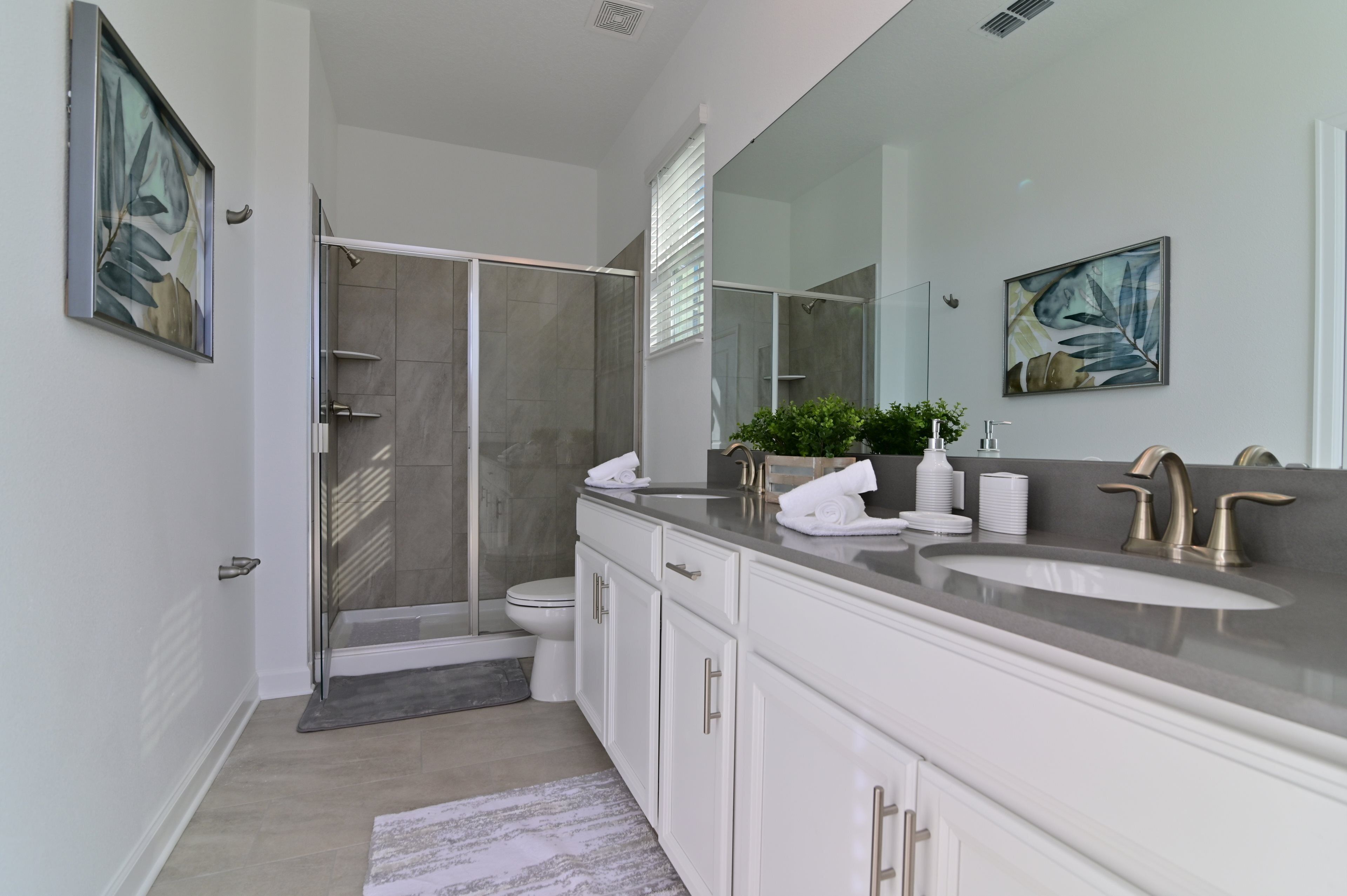 A modern bathroom with a walk-in shower, a large mirror, and a vanity with a sink and towel rack.